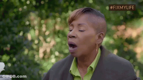 A Woman With A Shaved Head And A Green Shirt Is Yawning With Her Mouth Open . GIF