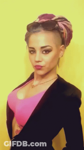 A Woman With A Shaved Head And A Pink Top GIF