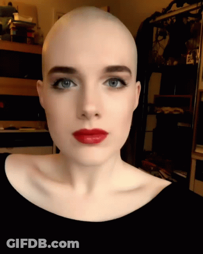 A Woman With A Shaved Head And Red Lips GIF