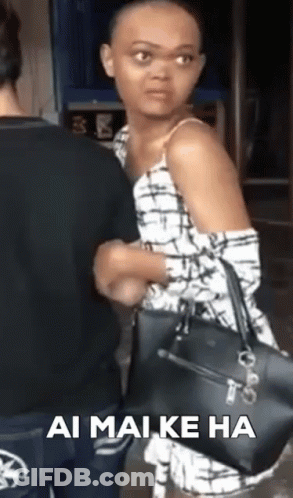 A Woman With A Shaved Head Is Holding A Black Purse While Standing Next To A Man . GIF