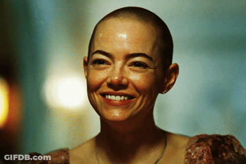 A Woman With A Shaved Head Is Smiling GIF