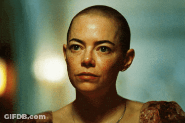 A Woman With A Shaved Head Is Wearing A Dress GIF
