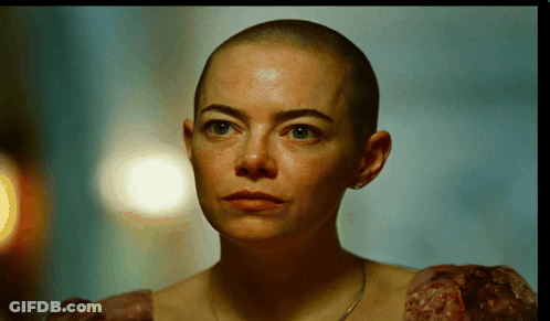 A Woman With A Shaved Head Is Wearing A Dress GIF