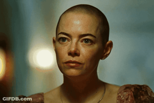 A Woman With A Shaved Head Is Wearing A Dress GIF