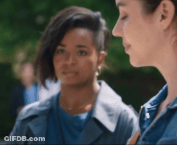 A Woman With A Shaved Head Looks At Another Woman GIF