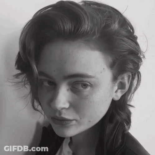 A Woman With A Shaved Head Looks At The Camera In A Black And White Photo GIF