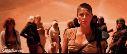 A Woman With A Shaved Head Stands In Front Of A Group Of People . GIF