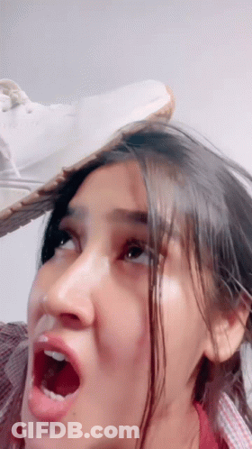 A Woman With A Shoe On Her Head Making A Funny Face GIF