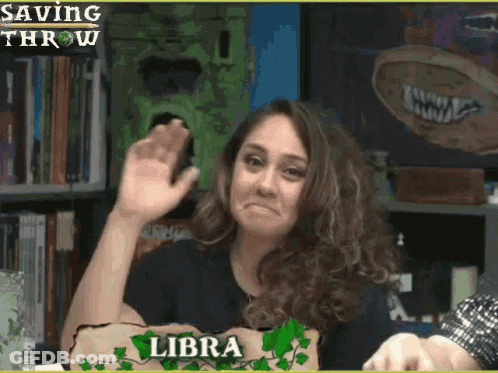 A Woman With A Sign That Says Libra Waves Her Hand GIF