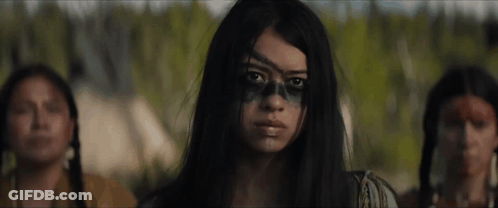 A Woman With A Skull Painted On Her Face Is Standing In Front Of Two Native American Women . GIF