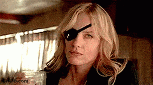A Woman With A Spoon In Her Eye Is Holding A Glass Of Water . GIF