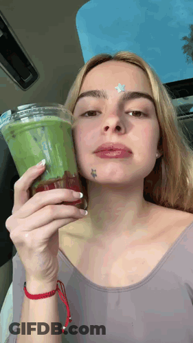 A Woman With A Star Tattoo On Her Forehead Is Holding A Cup Of Green Tea . GIF