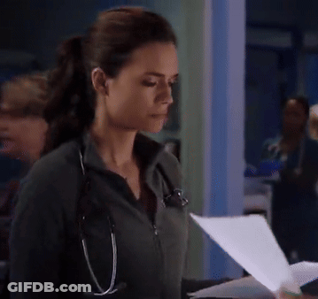 A Woman With A Stethoscope Around Her Neck Looks Down At A Piece Of Paper GIF