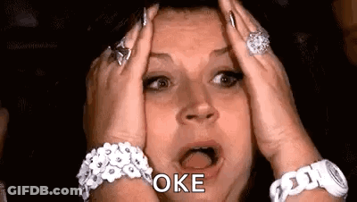 A Woman With A Surprised Look On Her Face Is Holding Her Head In Her Hands . GIF