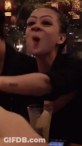 A Woman With A Tattoo On Her Arm Holds A Glass Of Water GIF