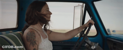 A Woman With A Tattoo On Her Arm Is Driving A Truck GIF
