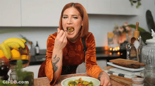 A Woman With A Tattoo On Her Arm Is Eating A Meal GIF
