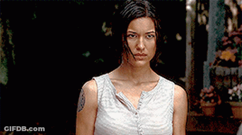 A Woman With A Tattoo On Her Arm Is Standing In A Dark Room GIF