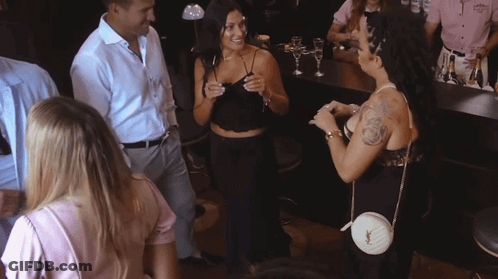 A Woman With A Tattoo On Her Arm Is Talking To A Man In A White Shirt GIF