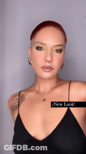 A Woman With A Tattoo On Her Arm Is Wearing A Black Tank Top And A Necklace GIF