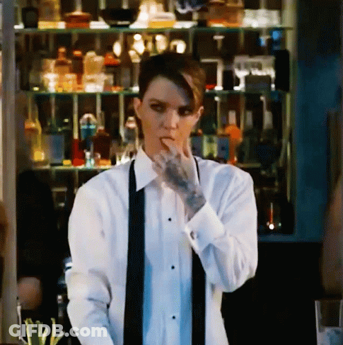 A Woman With A Tattoo On Her Arm Is Wearing A Tuxedo And A Black Tie GIF