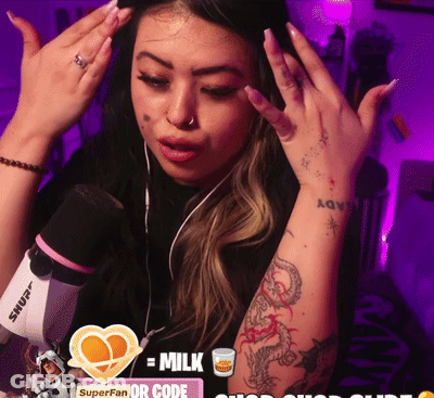 A Woman With A Tattoo On Her Arm Stands In Front Of A Microphone And A Sign That Says Milk GIF