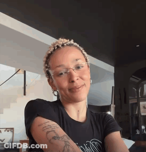 A Woman With A Tattoo On Her Arm Wearing A Black Shirt GIF