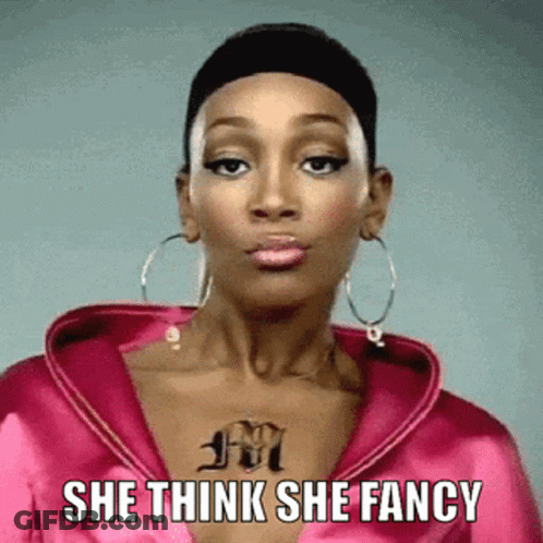 A Woman With A Tattoo On Her Chest Is Wearing A Pink Jacket And Hoop Earrings And Says She Think She Fancy GIF