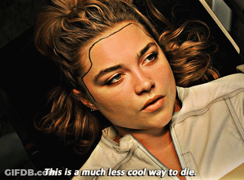 A Woman With A Tattoo On Her Forehead Is Laying Down And Says " This Is A Much Less Cool Way To Die " GIF