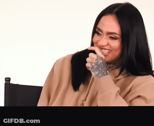 A Woman With A Tattoo On Her Hand Is Sitting In A Chair Laughing . GIF
