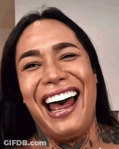 A Woman With A Tattoo On Her Neck Is Laughing With Her Mouth Wide Open GIF