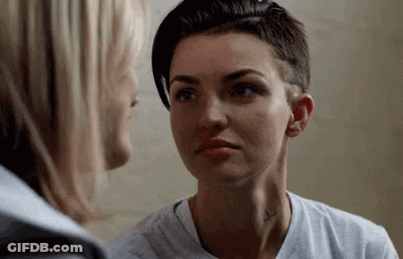 A Woman With A Tattoo On Her Neck Is Looking At Another Woman . GIF