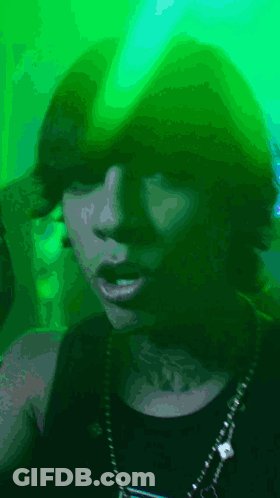 A Woman With A Tattoo On Her Neck Is Wearing A Green Hat GIF
