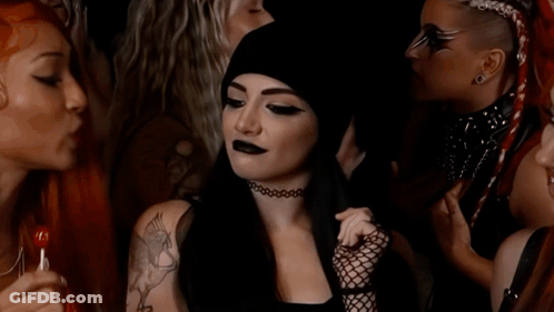 A Woman With A Tattoo On Her Shoulder Is Smiling In A Crowd Of People GIF