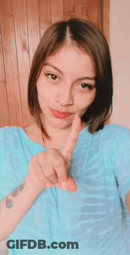 A Woman With A Tattoo On Her Wrist Giving A Peace Sign GIF