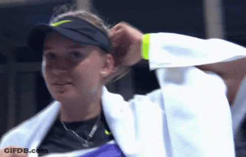 A Woman With A Towel Around Her Neck Is Wearing A Nike Hat GIF