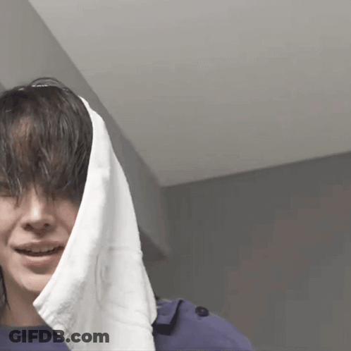 A Woman With A Towel Wrapped Around Her Head Is Smiling GIF