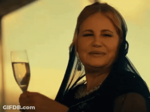 A Woman With A Veil On Her Head Is Holding A Glass Of Wine GIF