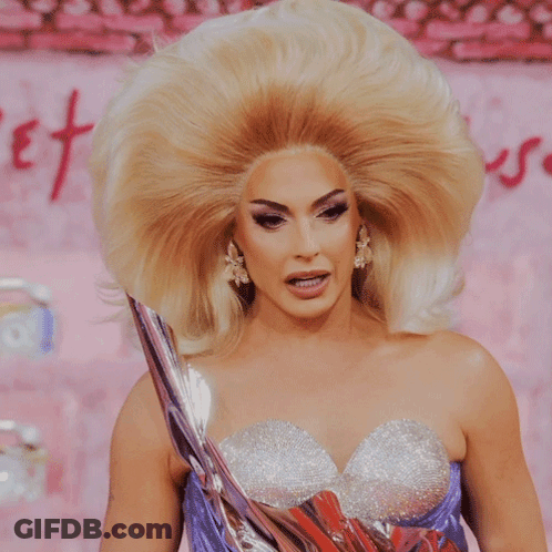 A Woman With A Very Large Blonde Wig And A Purple Dress GIF