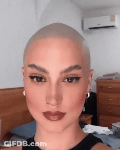 A Woman With A Very Shaved Head Is Wearing A Black Tank Top GIF