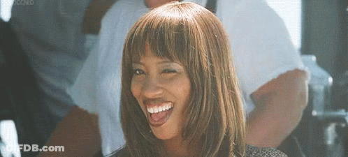 A Woman With A Wig And Bangs Is Smiling . GIF
