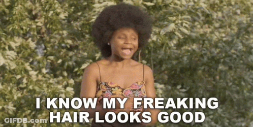 A Woman With An Afro Is Standing In Front Of A Tree And Says I Know My Freaking Hair Looks Good . GIF