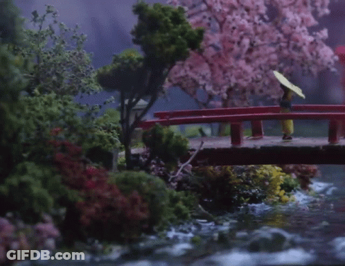 A Woman With An Umbrella Is Walking Across A Bridge GIF