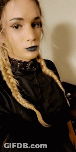 A Woman With Blonde Braids Is Wearing A Black Top GIF