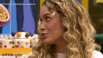 A Woman With Blonde Curly Hair Looks To The Side GIF