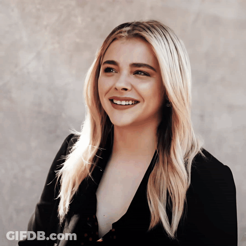 A Woman With Blonde Hair And A Black Jacket Smiles GIF
