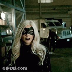A Woman With Blonde Hair And A Black Mask Is Standing In Front Of A Truck . GIF
