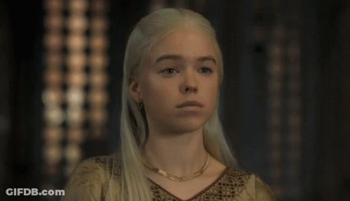 A Woman With Blonde Hair And A Gold Necklace Looks At The Camera GIF
