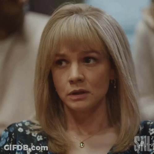 A Woman With Blonde Hair And A Necklace Is Making A Funny Face . GIF
