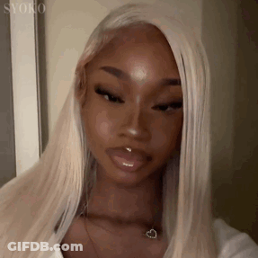A Woman With Blonde Hair And A Nose Ring Is Wearing A White Shirt And A Heart Necklace . GIF